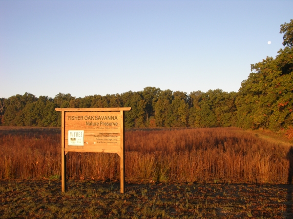 Preserve sign at sunset, with meadow, woods, and full moon in background